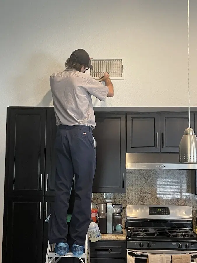 Technician inspecting an air vent during HVAC service in Weddington